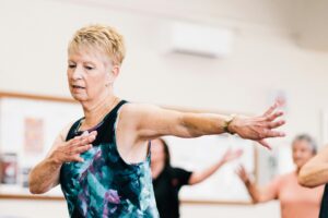 Senior woman participating in a lively fitness class indoors, embracing positive aging.