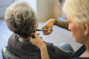 Hairdresser cutting the hair of a senior woman in a salon setting. Professional and detailed shot.